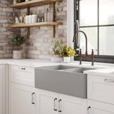 Modern kitchen with gray farmhouse sink, wooden shelves, and brick wall.