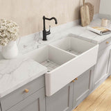 Modern kitchen with a white farmhouse sink, marble countertop, and light gray cabinets.