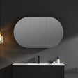 Bathroom with a large oval mirror above a vanity.