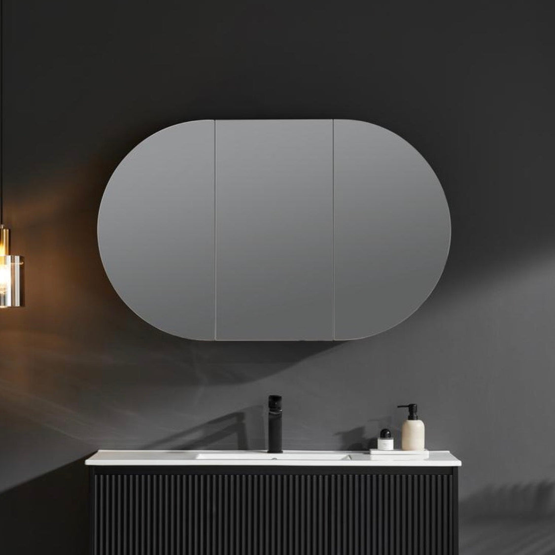 Bathroom with a large oval mirror above a vanity.