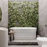 Bathroom with a freestanding bathtub against a green leafy wall.