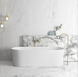 Modern bathroom with a freestanding bathtub, marble wall, and gold fixtures.