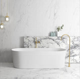 Modern bathroom with a freestanding bathtub, marble wall, and gold fixtures.