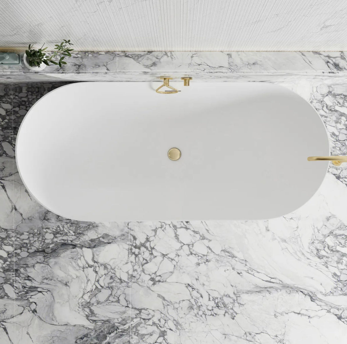 White oval bathtub with gold fixtures on a marble countertop