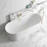 White freestanding bathtub with gold fixtures on a marble floor and wall.
