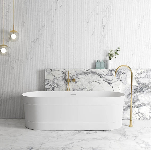 Modern bathroom with a white freestanding bathtub, marble wall, and gold fixtures.