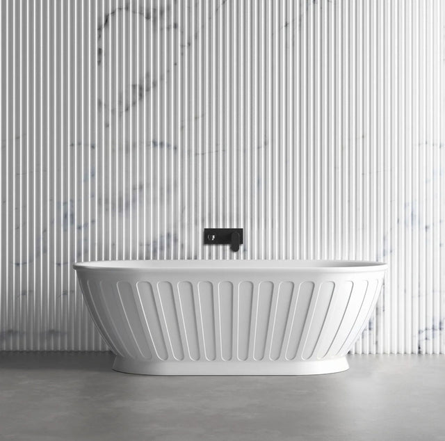 White freestanding bathtub against a marble-patterned wall