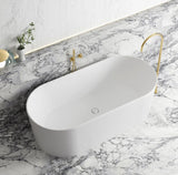 White freestanding bathtub with gold faucet on a marble countertop