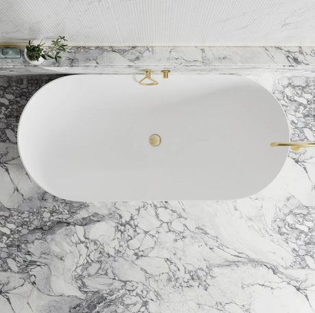 White oval sink with gold fixtures on a marble countertop