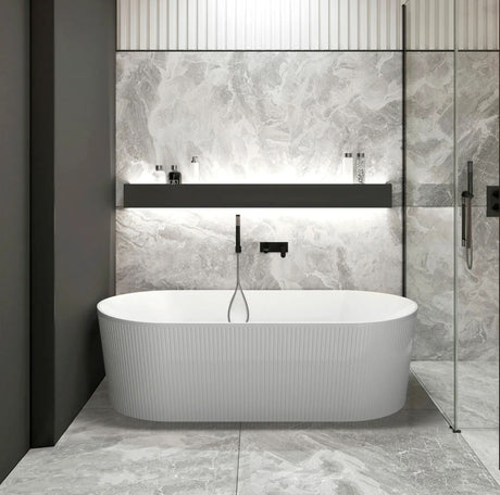 Modern bathroom with a freestanding bathtub against a tiled wall.