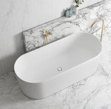 White freestanding bathtub with gold fixtures on a marble bathroom floor.