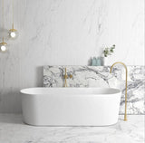 Modern bathroom with a freestanding bathtub, marble wall, and gold fixtures.