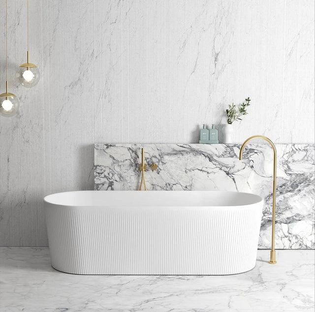 Modern bathroom with a freestanding bathtub, marble wall, and gold fixtures.