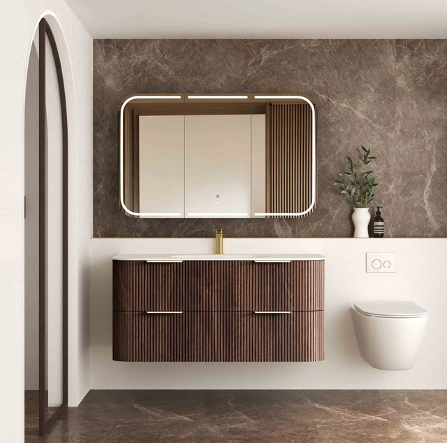 Modern bathroom with wooden vanity, mirror, and toilet against a marble wall.