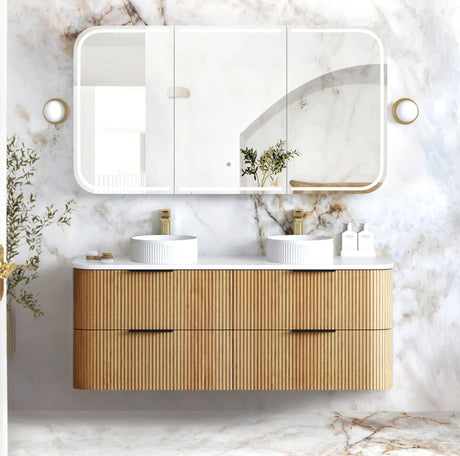 Bathroom vanity with wooden cabinet, white countertop, and mirror against a marble wall.