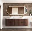 Bathroom vanity with wooden finish, two sinks, and a large mirror on a marble wall.