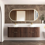 Bathroom vanity with wooden finish, two sinks, and a large mirror on a marble wall.