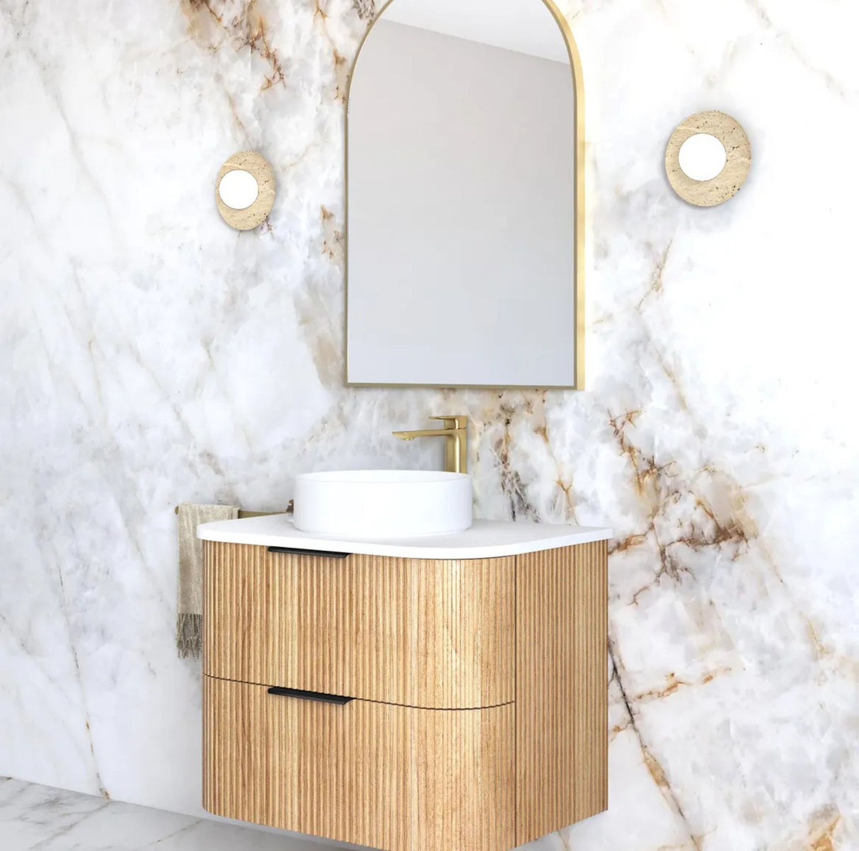 Bathroom vanity with wooden cabinet, white sink, and gold faucet against a marble wall.
