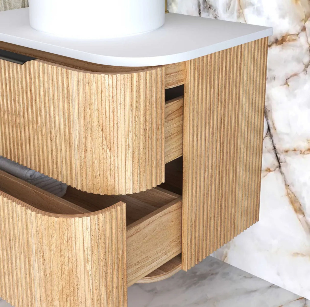 Wooden bathroom vanity with white countertop against a marble wall.