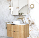 Bathroom vanity with wooden cabinet, white countertop, and mirror on marble wall.
