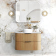 Bathroom vanity with wooden cabinet, white countertop, and mirror on a marble wall.