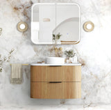 Bathroom vanity with wooden cabinet, white countertop, and mirror on a marble wall.