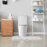 White toilet in a bathroom with a wicker laundry basket and a white shelf with towels.