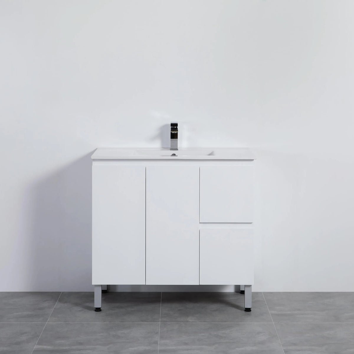 White bathroom vanity with sink against a plain white wall.