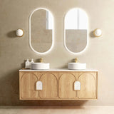 Bathroom vanity with two round sinks, wooden cabinet, and illuminated mirrors.