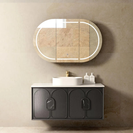 Bathroom setup with a black vanity, white sink, and oval mirror on a beige wall.