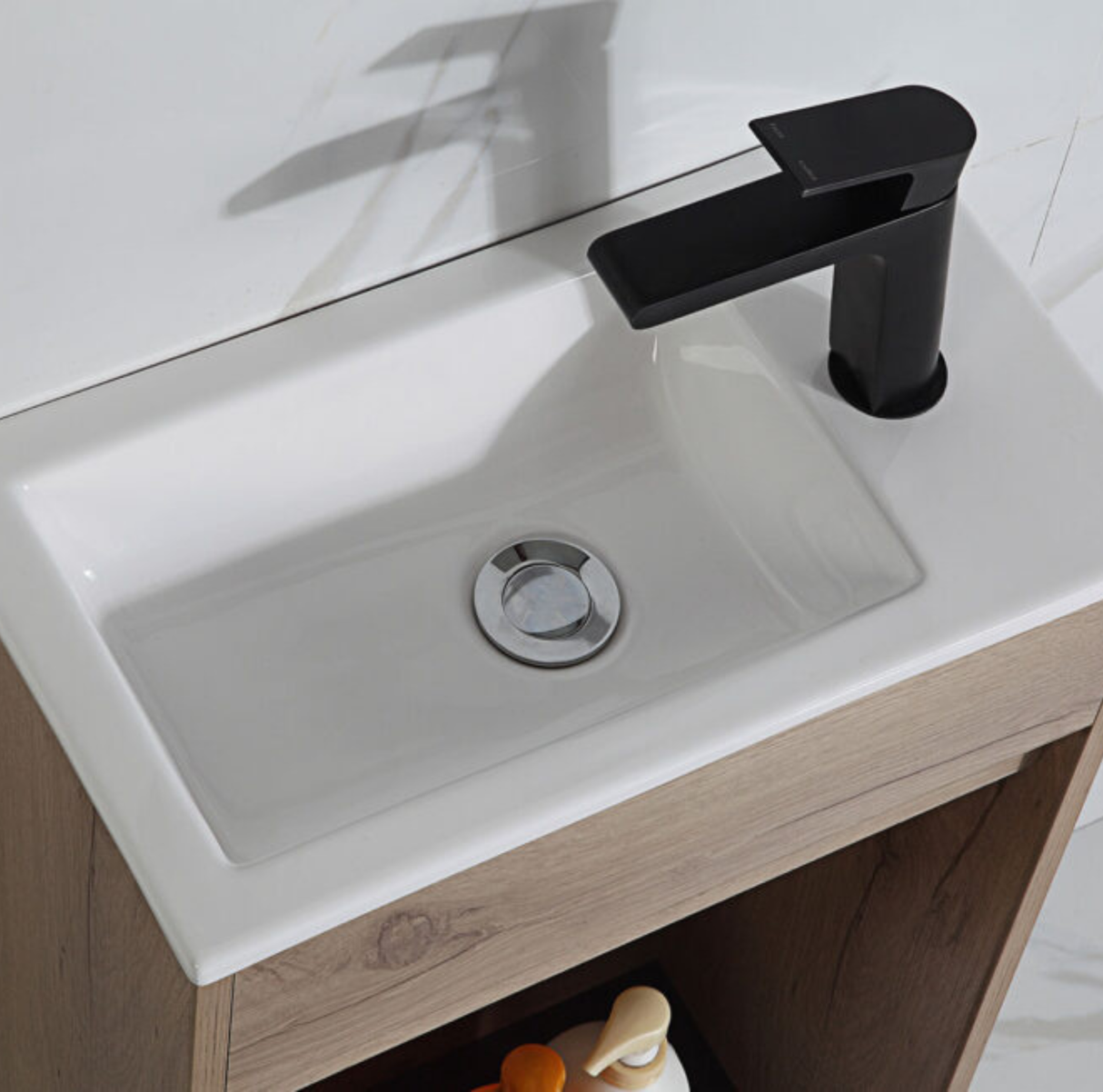 White sink with a black faucet on a wooden vanity