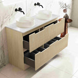 Bathroom vanity with white countertop, black fixtures, and wooden drawers.