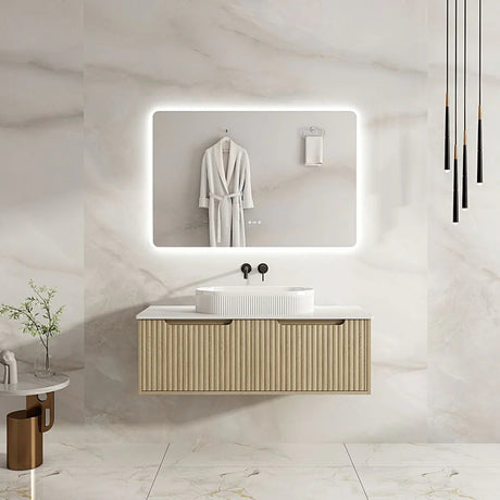 Bathroom vanity with illuminated mirror and white robe on a marble wall.