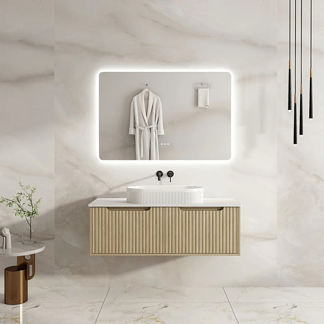 Bathroom vanity with illuminated mirror and white robe on a marble wall.