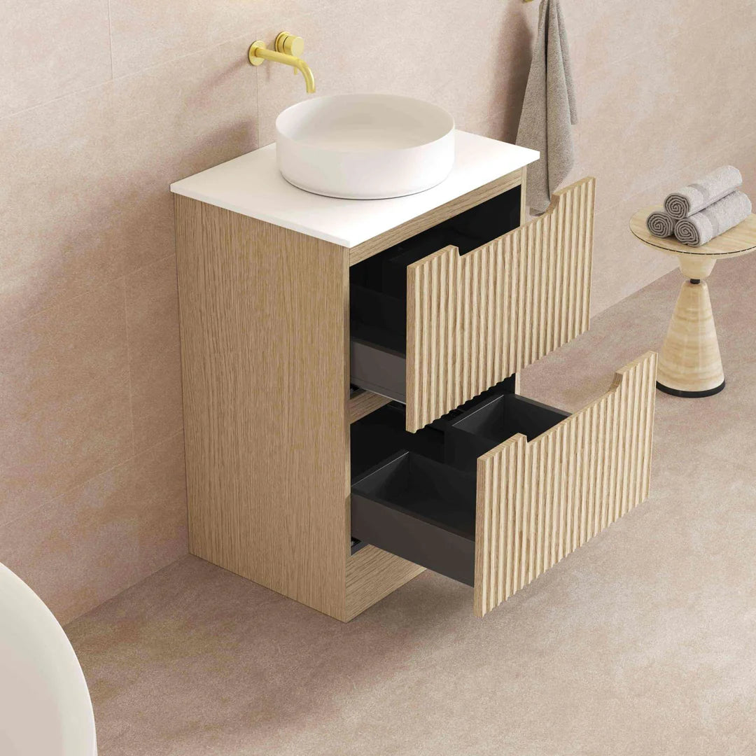 Bathroom vanity with open drawers and a white sink on a marble wall background