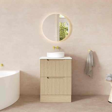 Bathroom with beige vanity, round mirror, and towel.