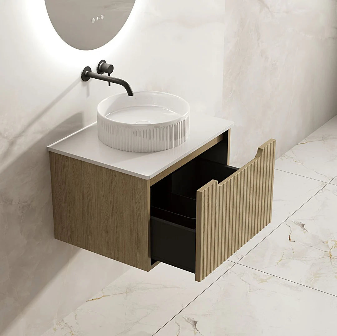 Bathroom vanity with a sink and open drawer against a white tiled wall.