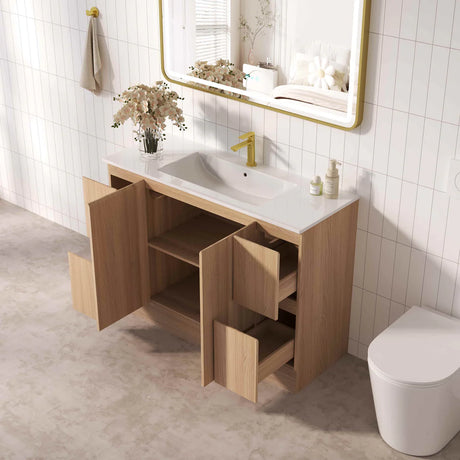 Bathroom with wooden vanity, sink, and toilet against a tiled wall.