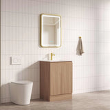 Bathroom with wooden vanity, mirror, and toilet against a tiled wall.