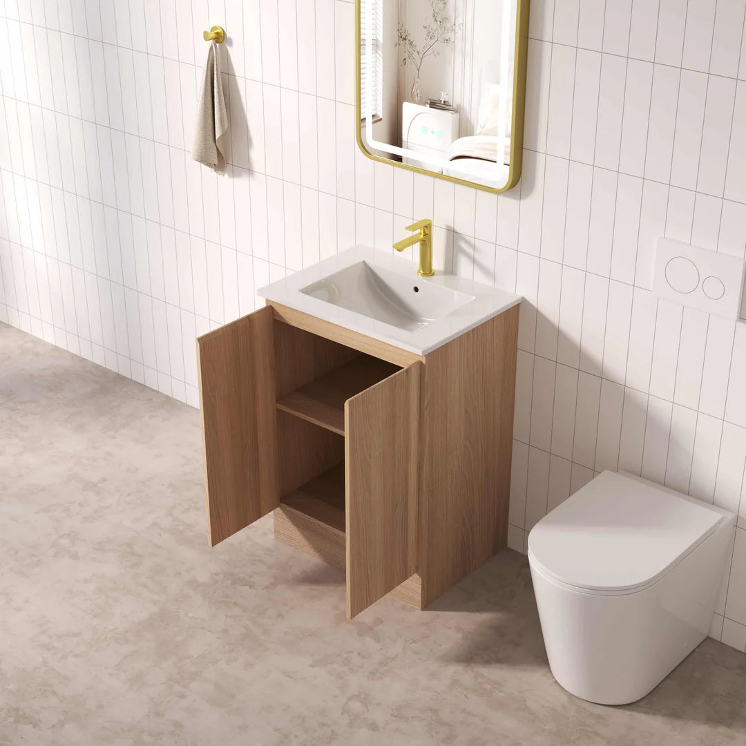 Bathroom with wooden vanity, sink, and toilet against a tiled wall.
