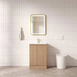 Bathroom with wooden vanity, mirror, and toilet against a tiled wall.