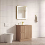 Bathroom setup with wooden vanity, mirror, and toilet against a tiled wall.