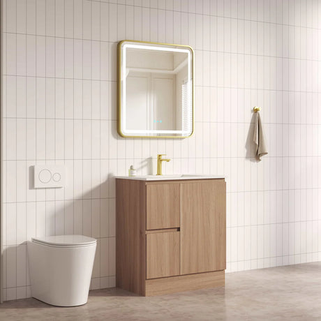 Bathroom setup with wooden vanity, mirror, and toilet against a tiled wall.