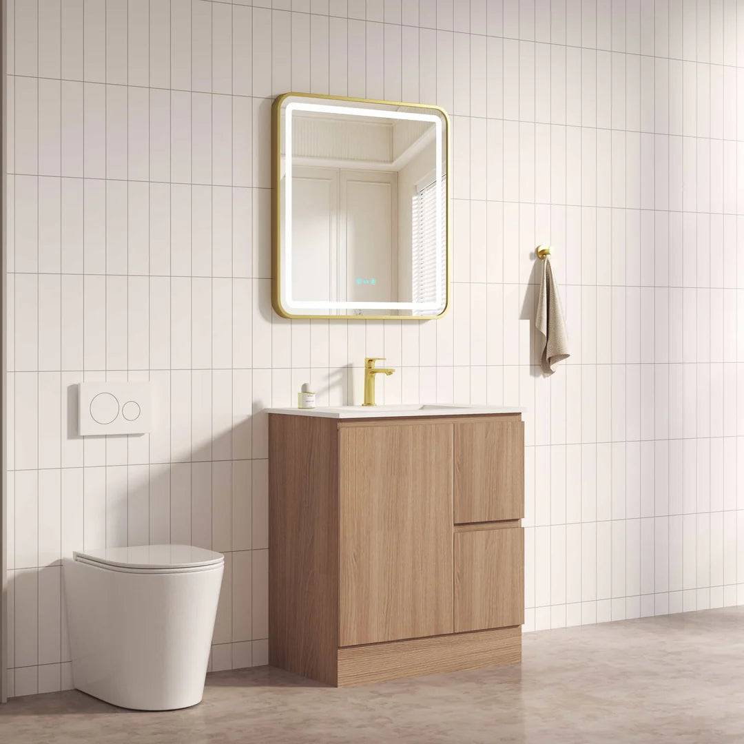 Bathroom setup with wooden vanity, mirror, and toilet against a tiled wall.