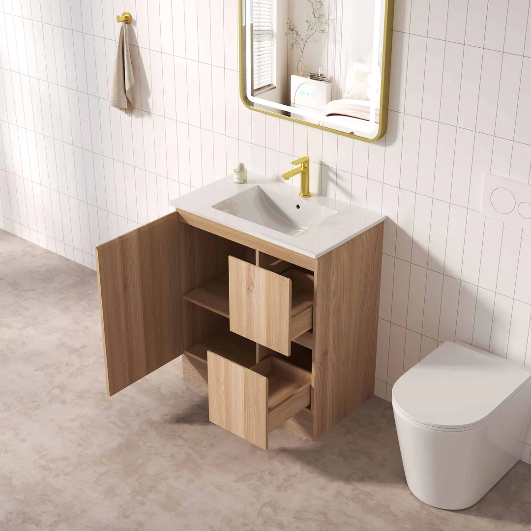 Bathroom with wooden vanity, sink, and toilet against a tiled wall.