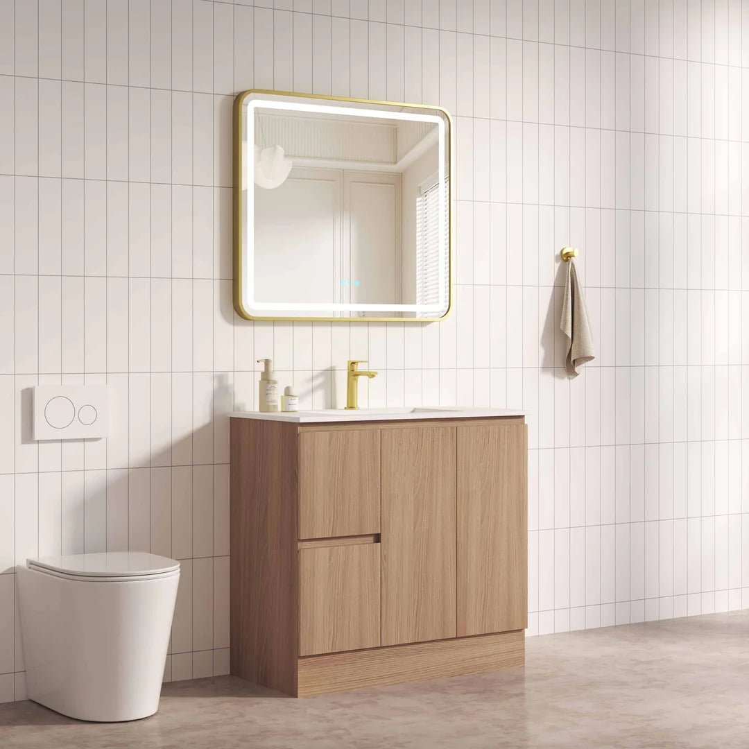 Bathroom with wooden vanity, mirror, and toilet against a tiled wall.
