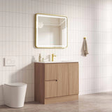 Bathroom with wooden vanity, mirror, and toilet against a tiled wall.