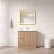 Bathroom with wooden vanity, mirror, and toilet against a tiled wall.