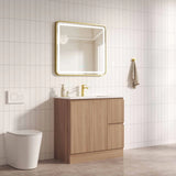 Bathroom with wooden vanity, mirror, and toilet against a tiled wall.