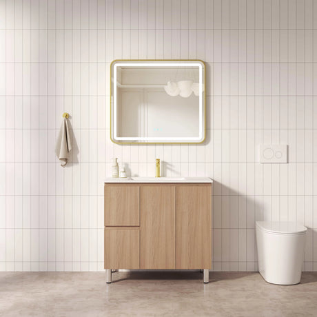 Bathroom with wooden vanity, mirror, and toilet against a tiled wall.